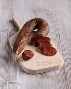 chorizo de león de herradura presentado en pieza y algunos trozos sobre tabla de madera con algunos
