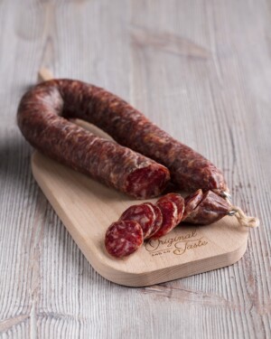 Salchichon Embutido de León de herradura presentado en pieza y con algunos trozos sobre tabla de madera